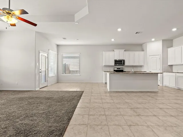 a view of kitchen with granite countertop cabinets and refrigerator