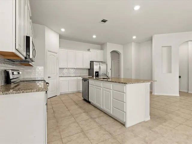 a kitchen with stainless steel appliances granite countertop a stove top oven a sink and a refrigerator