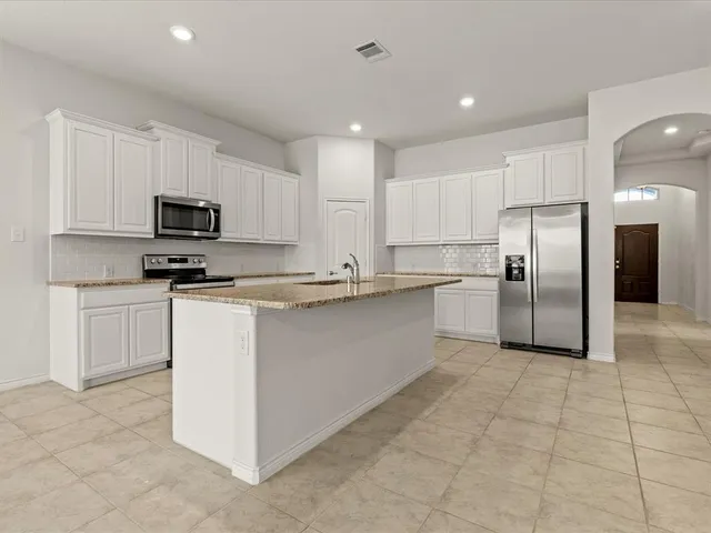 a kitchen with granite countertop a refrigerator and a stove top oven