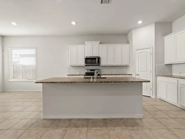 a kitchen with granite countertop a stove a sink and a microwave