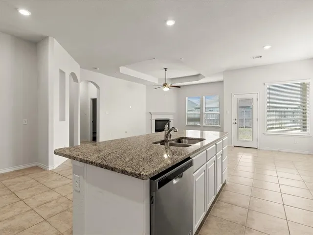 a kitchen with a granite countertop sink and refrigerator