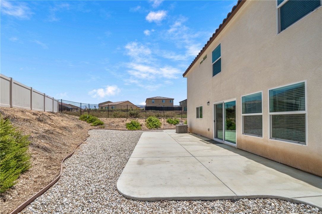 20130 Curaco Court Riverside, CA 92507 - Photo 40 of 43 Backyard patio along the home with gravel landscaping and perimeter fencing.