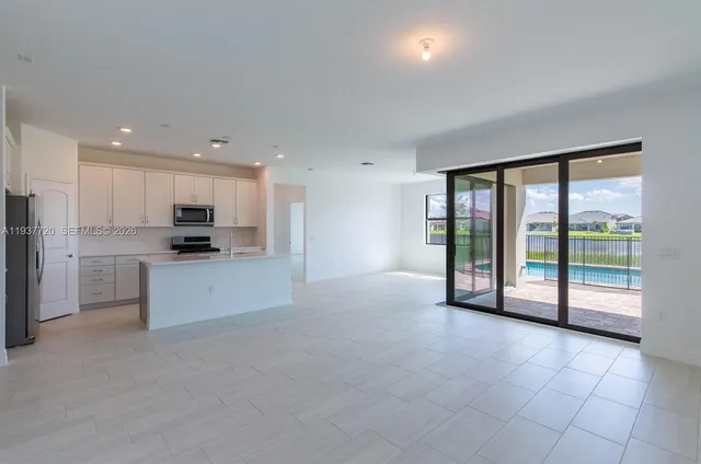 a large kitchen with stainless steel appliances granite countertop a refrigerator oven a sink and a large window