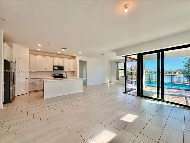 a large kitchen with stainless steel appliances kitchen island granite countertop a refrigerator a stove a sink and a large window