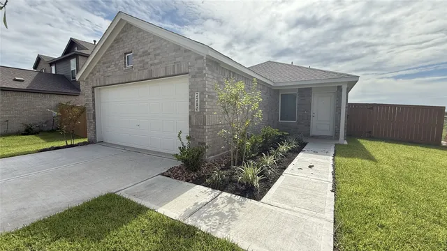 a view of a house with brick walls plants and large tree