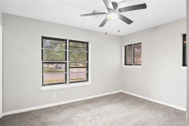 an empty room with a window and a ceiling fan