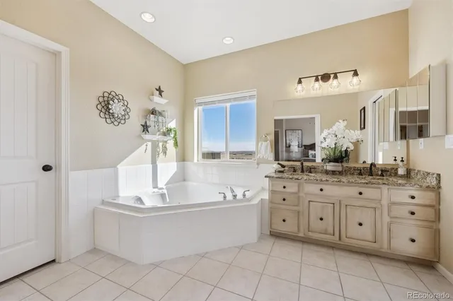 a spacious bathroom with a granite countertop sink a mirror and bathtub