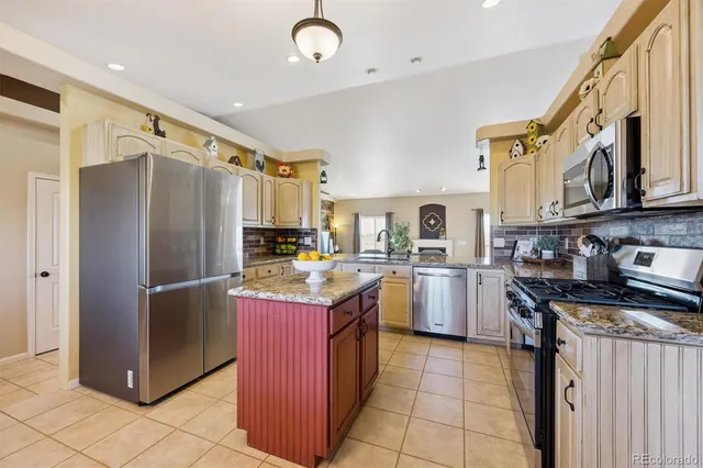 a kitchen with stainless steel appliances granite countertop a refrigerator and a stove top oven