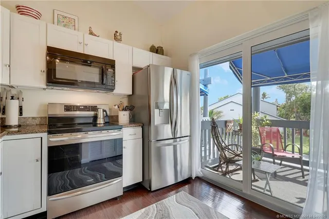 a kitchen with stainless steel appliances granite countertop a refrigerator and a wooden floor