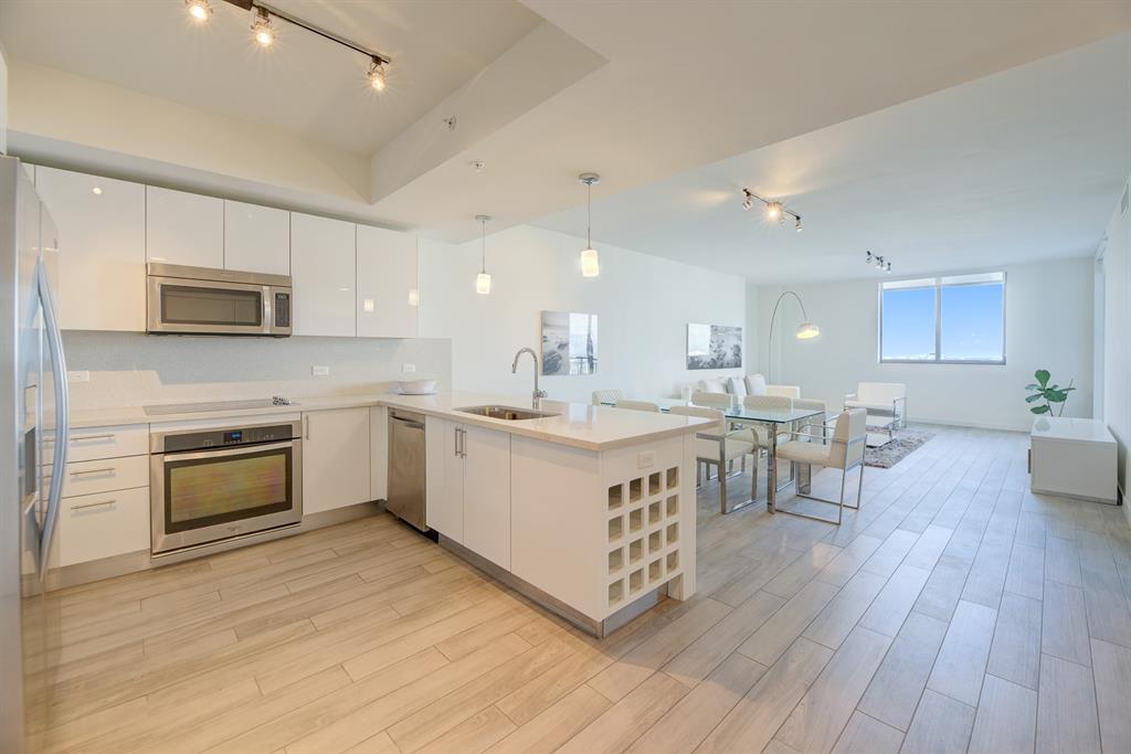 999 Southwest 1st Avenue, Unit 2913 Miami, FL 33130 - Photo 4 of 36 a kitchen with stainless steel appliances granite countertop a stove top oven a sink dishwasher and a refrigerator with wooden floor