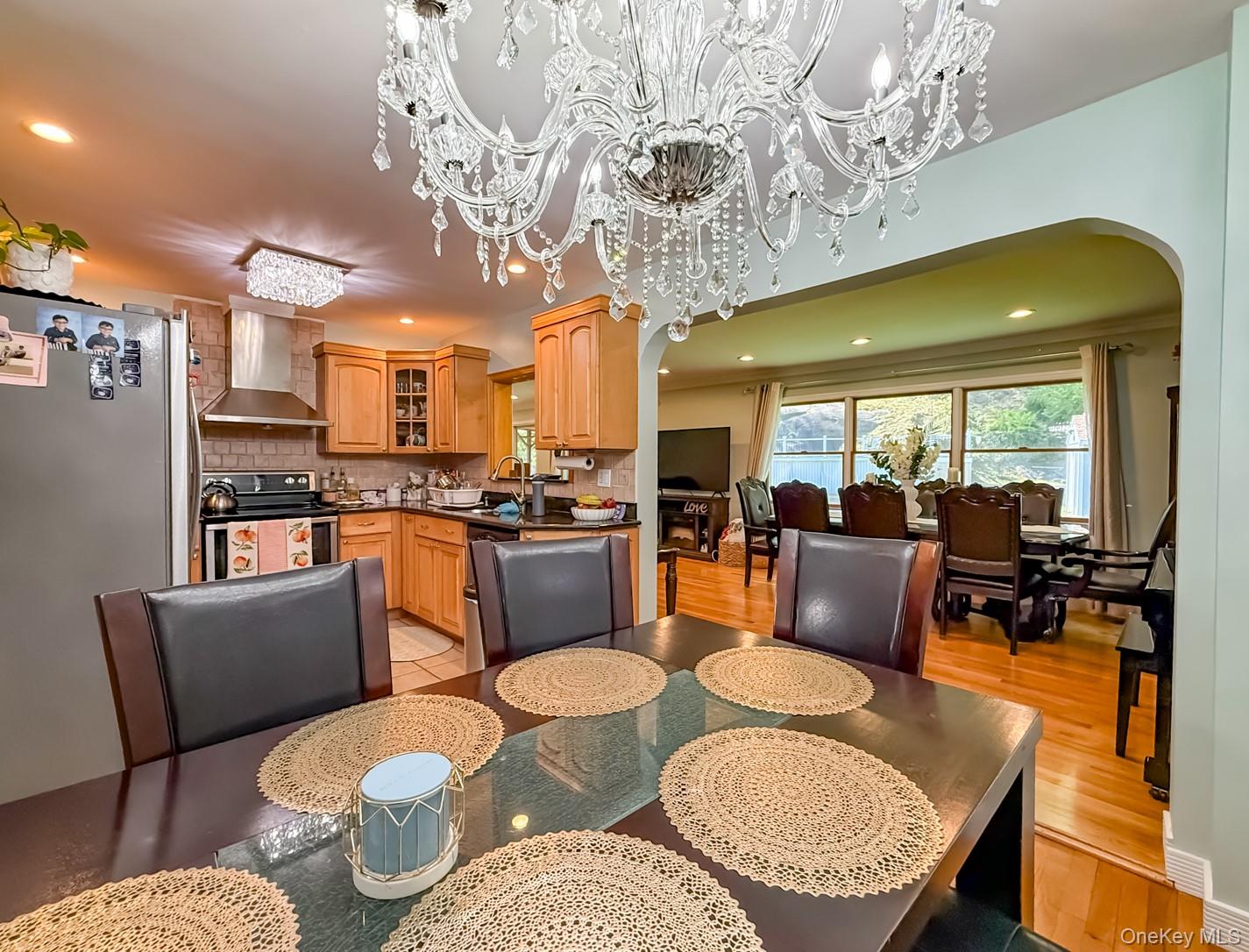 49 Meadow Road Montrose, NY 10548 - Photo 11 of 50 Dining area with a crystal chandelier, wood-finish flooring, and an arched entryway to an additional room with expansive windows