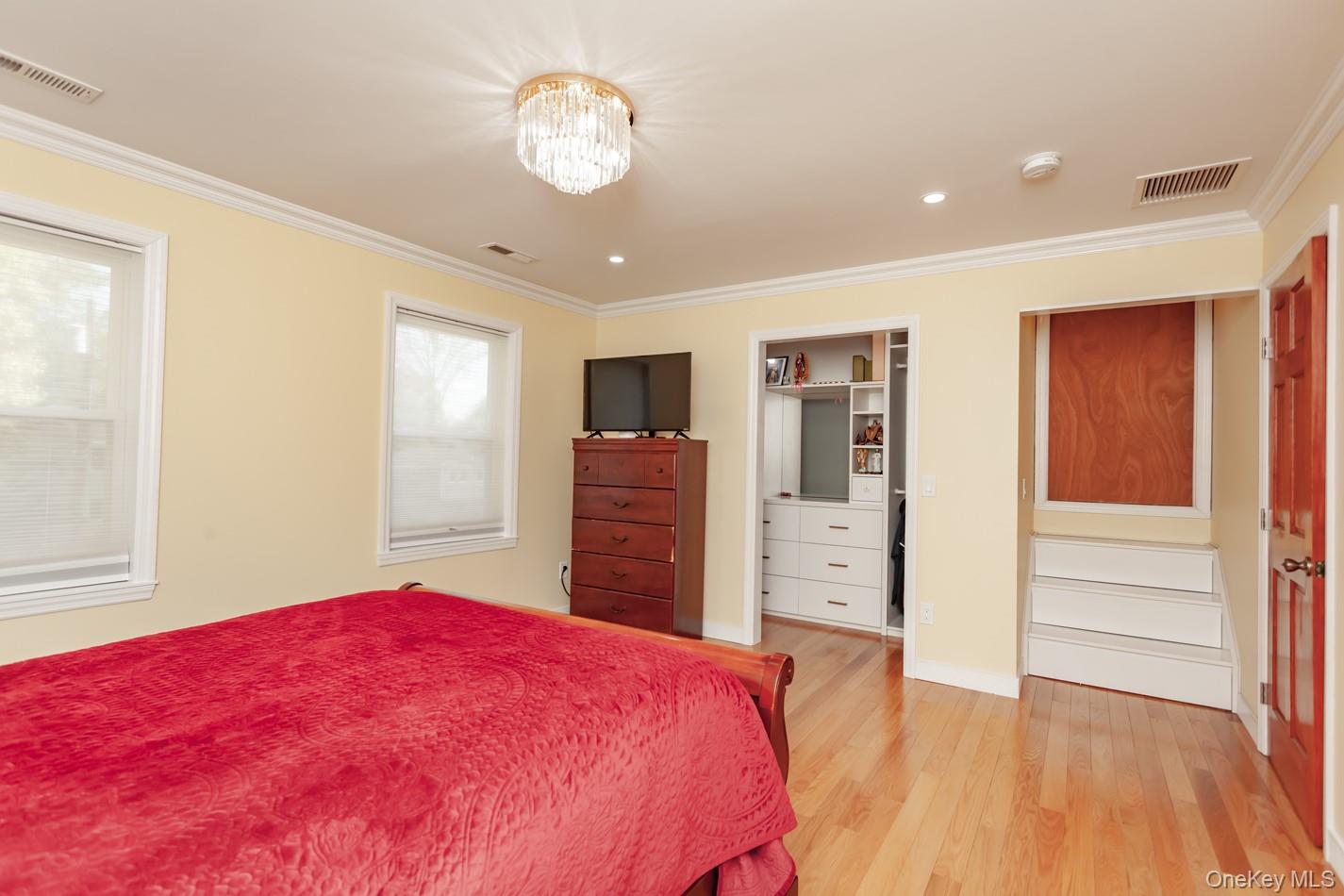 49 Meadow Road Montrose, NY 10548 - Photo 18 of 50 Bedroom featuring hardwood flooring, two windows, a crystal chandelier, recessed lighting, and a built-in closet system