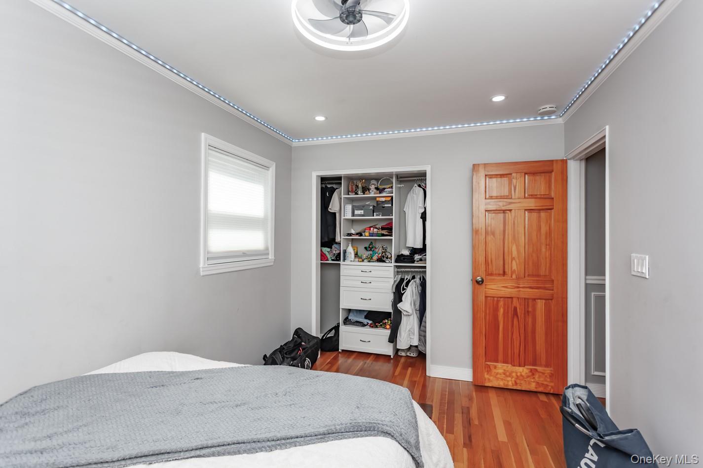 49 Meadow Road Montrose, NY 10548 - Photo 33 of 50 Hardwood flooring, crown molding with accent lighting, built-in closet organization, contemporary ceiling fan, and recessed lighting