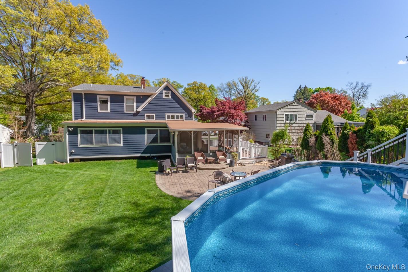 49 Meadow Road Montrose, NY 10548 - Photo 4 of 50 Spacious backyard featuring an above-ground pool, a paver patio, and a screened-in porch with a ceiling fan