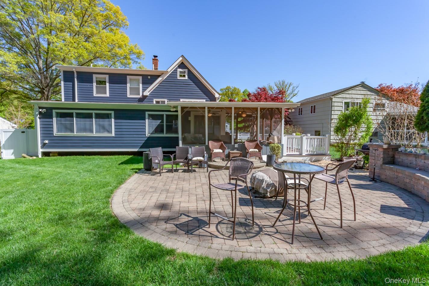 49 Meadow Road Montrose, NY 10548 - Photo 43 of 50 Expansive backyard featuring a circular paver patio, a screened-in porch, a landscaped retaining wall, and a verdant lawn