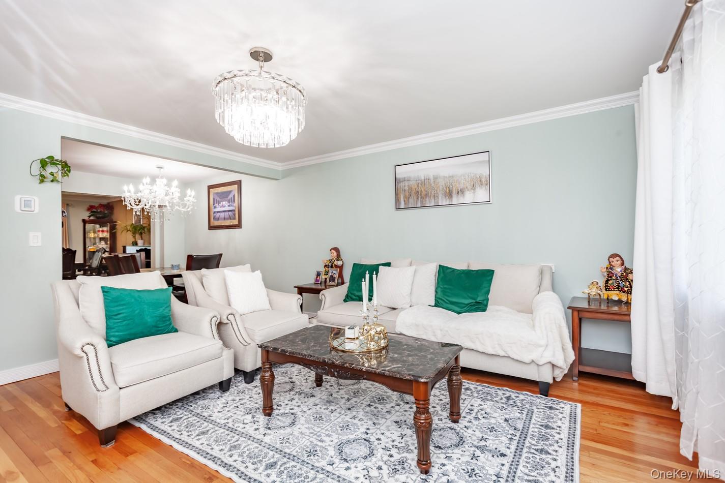 49 Meadow Road Montrose, NY 10548 - Photo 7 of 50 Living area featuring wood-finish flooring, a crystal chandelier, crown molding, and a light-toned wall color