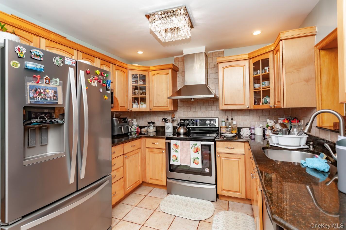 49 Meadow Road Montrose, NY 10548 - Photo 9 of 50 Kitchen featuring light wood cabinetry with glass-front accents, dark granite countertops, and stainless steel appliances