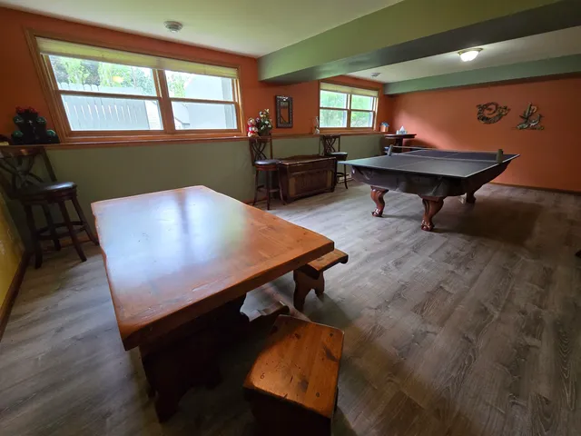 a living room with furniture pool table wooden floor and windows