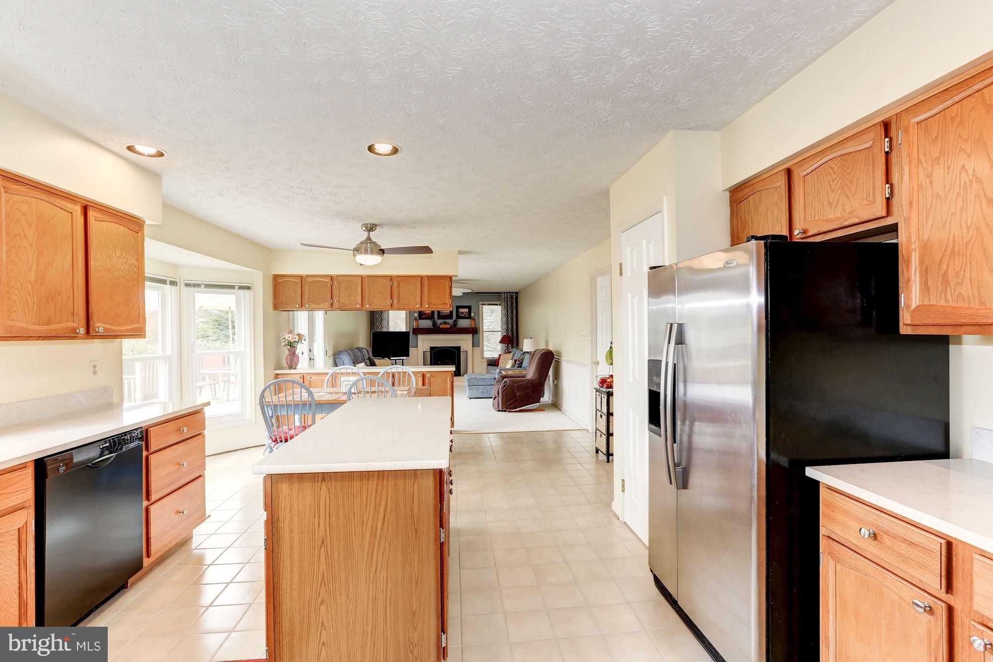 17005 Spates Hill Road Poolesville, MD 20837 - Photo 5 of 25 a view of a kitchen with kitchen island a counter top space a refrigerator a stove a sink dishwasher and wooden cabinets with large windows