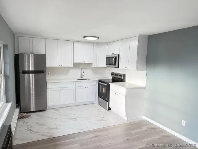 a kitchen with white cabinets and stainless steel appliances