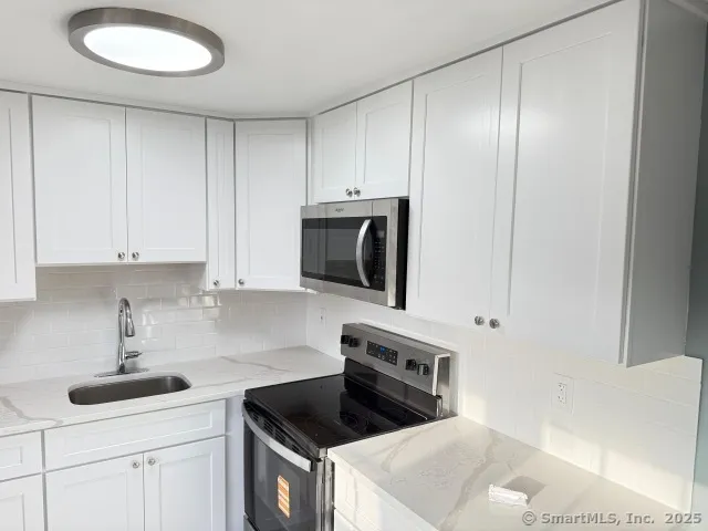a kitchen with white cabinets and sink