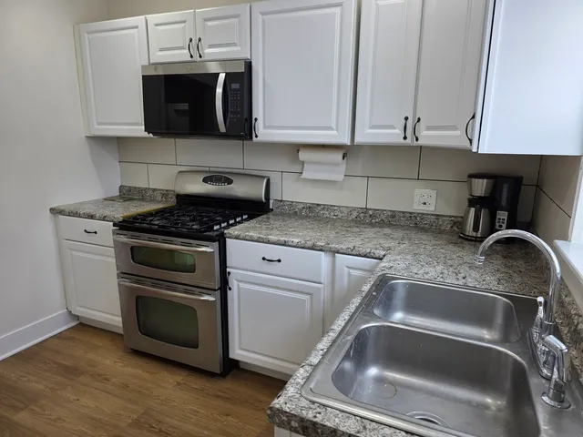 a kitchen with granite countertop a sink stainless steel appliances and cabinets