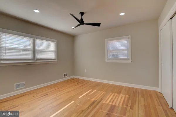 a view of empty room with wooden floor and fan