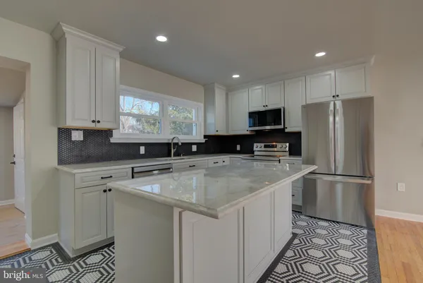 a kitchen with a sink a center island cabinets and a refrigerator