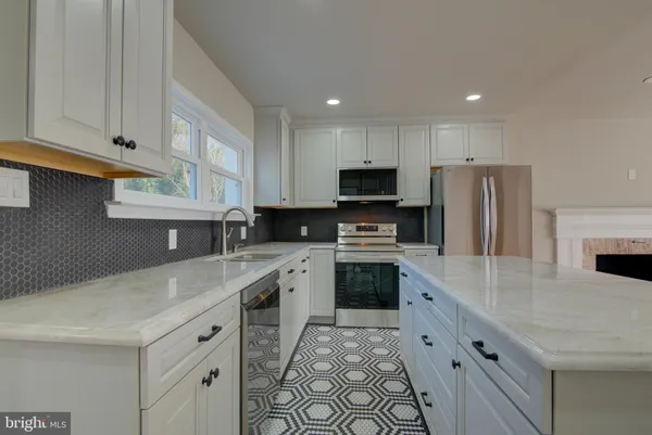 a kitchen with granite countertop a sink stainless steel appliances and white cabinets