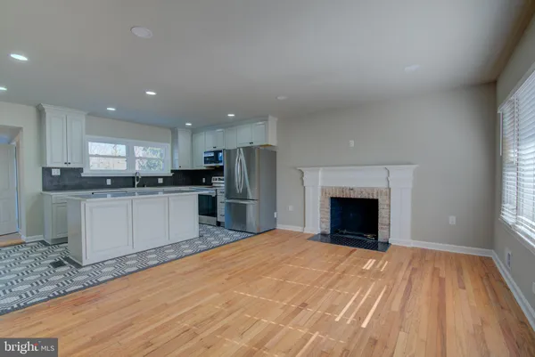 a large kitchen with granite countertop a stove top oven a sink dishwasher and a refrigerator with wooden floor