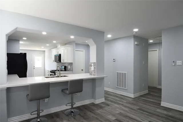 a large white kitchen with stainless steel appliances kitchen island granite countertop a sink and cabinets