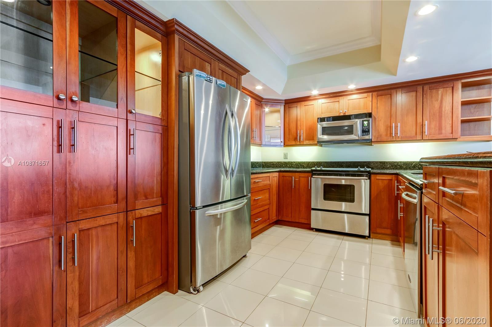 520 Brickell Key Drive, Unit A1702 Miami, FL 33131 - Photo 5 of 13 a kitchen with stainless steel appliances granite countertop a refrigerator and wooden cabinets