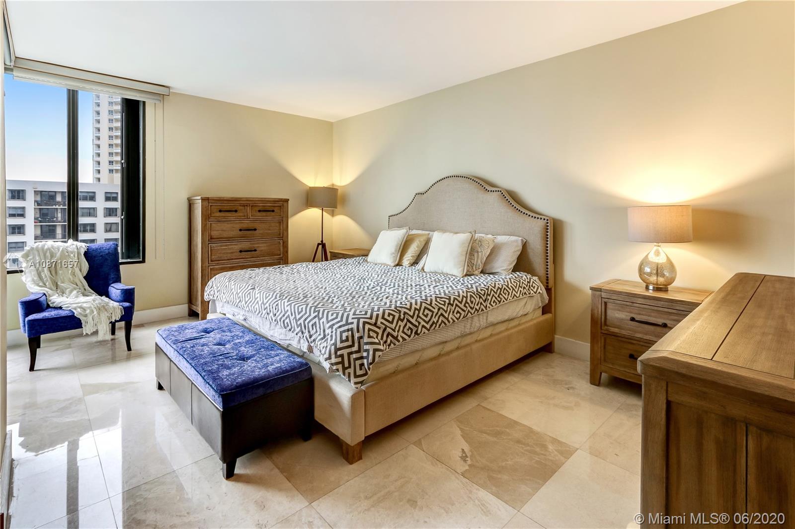 520 Brickell Key Drive, Unit A1702 Miami, FL 33131 - Photo 7 of 13 a spacious bedroom with a bed a table and a dresser next to a window