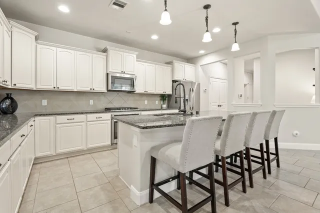 a kitchen with a white cabinets and chairs