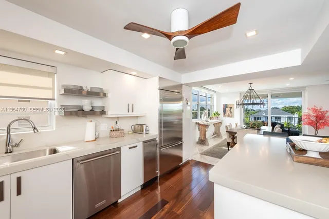a large white kitchen with a large window appliances and cabinets