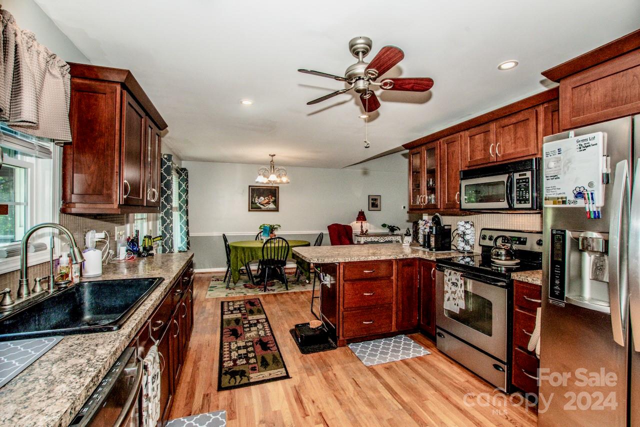 3510 Mack Ballard Road Maiden, NC 28650 - Photo 10 of 26 a kitchen with stainless steel appliances granite countertop a stove top oven a sink dishwasher a dining table and chairs with wooden floor