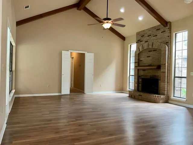 an empty room with wooden floor closet and windows