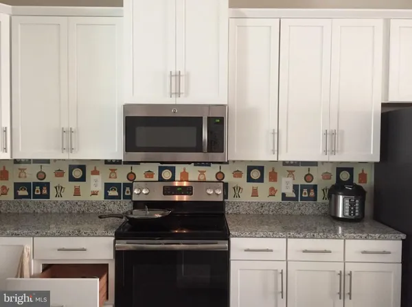 a kitchen with granite countertop white cabinets and black appliances