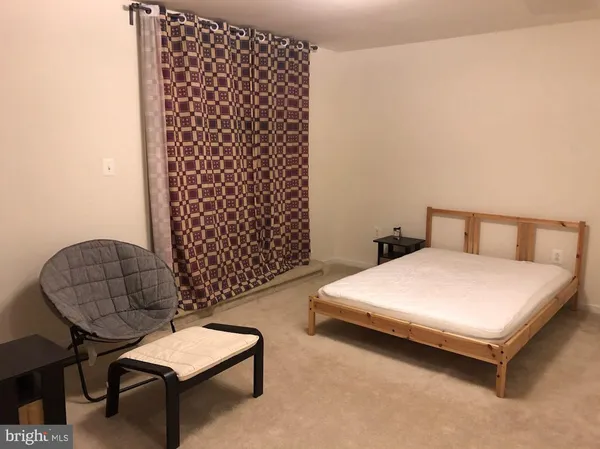 a bedroom with a bed and a chair with the wooden floor