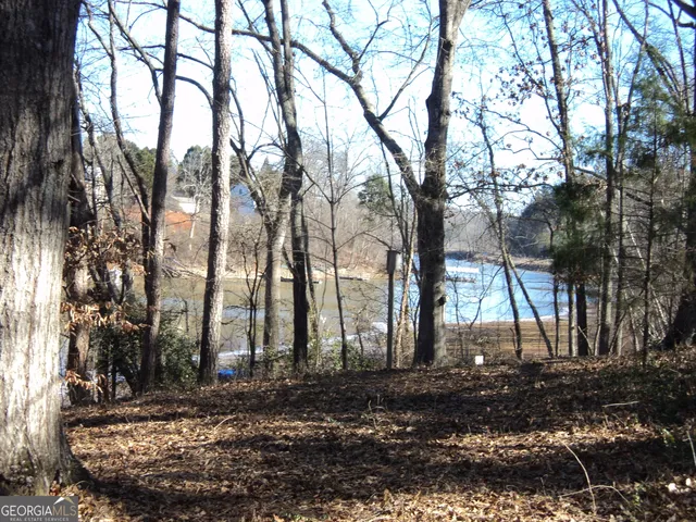 a view of a brick house with a yard and large trees