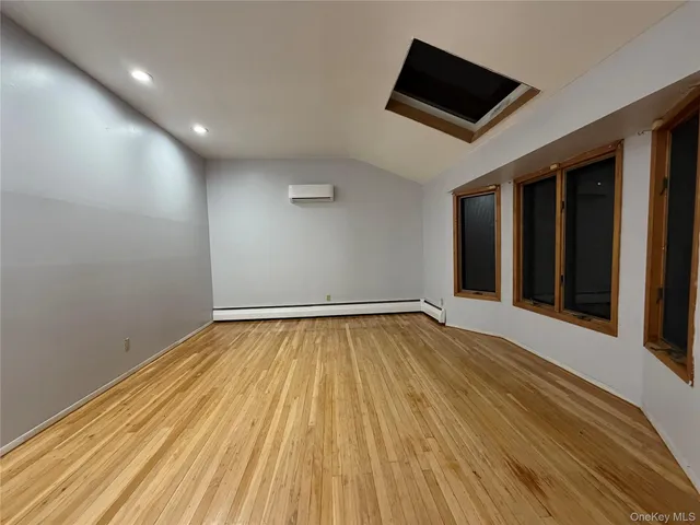 an empty room with wooden floor and natural light