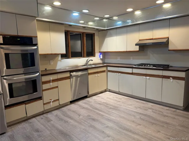 a kitchen with stainless steel appliances granite countertop a stove a sink and a microwave