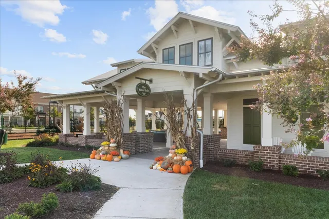 a front view of a house with a yard and potted plants and a tree