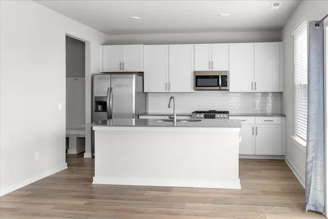 a kitchen with kitchen island white cabinets and stainless steel appliances