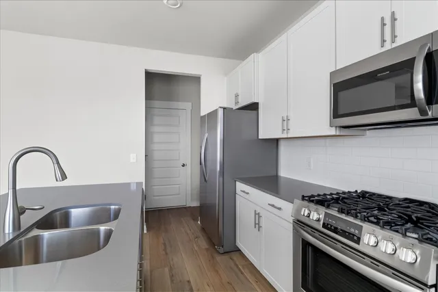 a kitchen with stainless steel appliances a stove a microwave a sink and cabinets