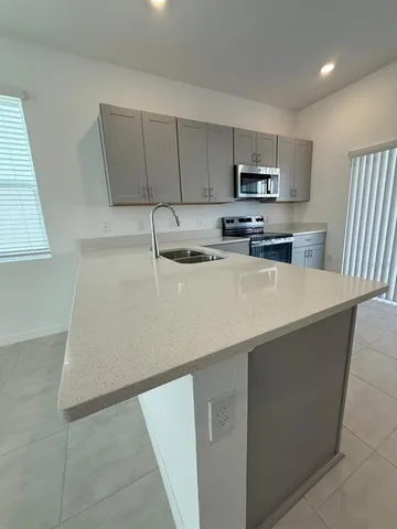 a kitchen with stainless steel appliances a sink a stove top oven a counter space and cabinets