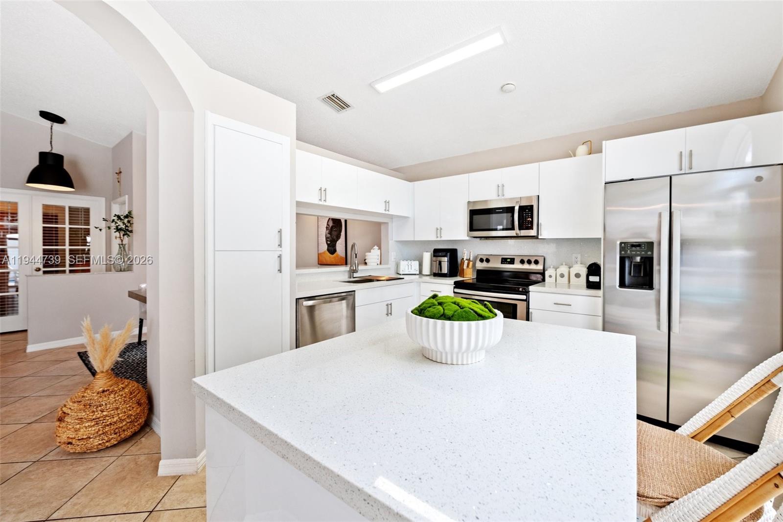955 Azure Lane Weston, FL 33326 - Photo 14 of 34 a kitchen with a refrigerator a stove top oven a sink dishwasher and white cabinets with wooden floor