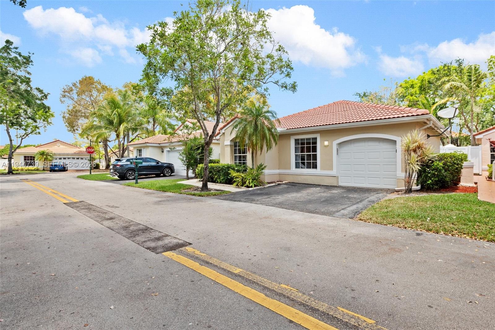 955 Azure Lane Weston, FL 33326 - Photo 2 of 34 a yellow house with trees in front of it