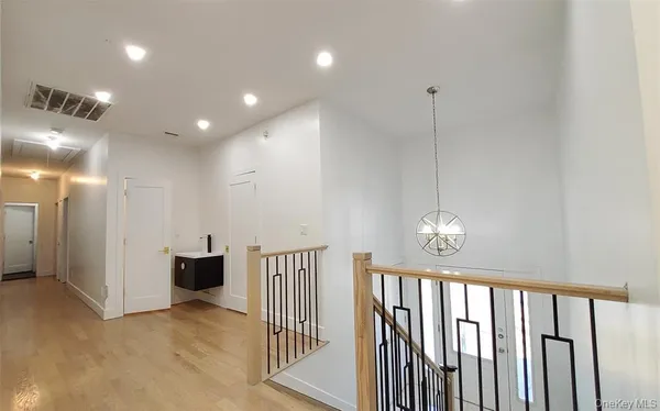 a view of a hallway with wooden floor and a bathroom