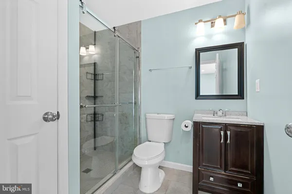 a bathroom with a toilet sink vanity granite and shower